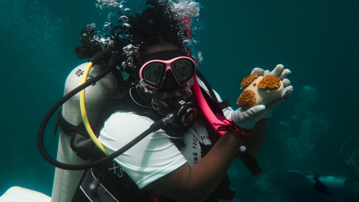 Black in Marine Science member holds a coral during the restoration dive