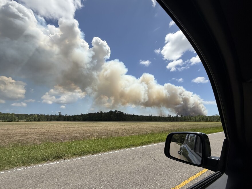 A plume of smoke rises over a field.