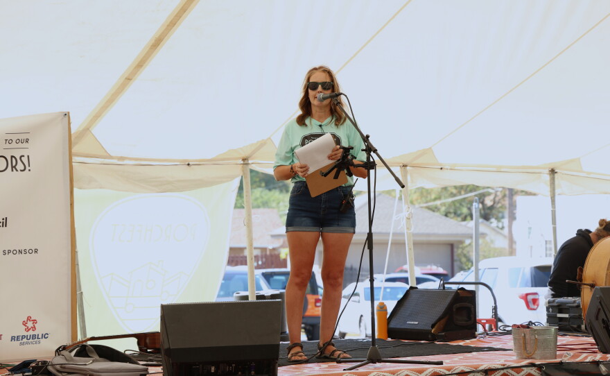 Angela Hudson speaks at the opening announcements of the 10th annual North Heights Porchfest on Oct. 10, 2026. She's standing on a flat bed trailer that's been made into a stage, speaking into a microphone.
