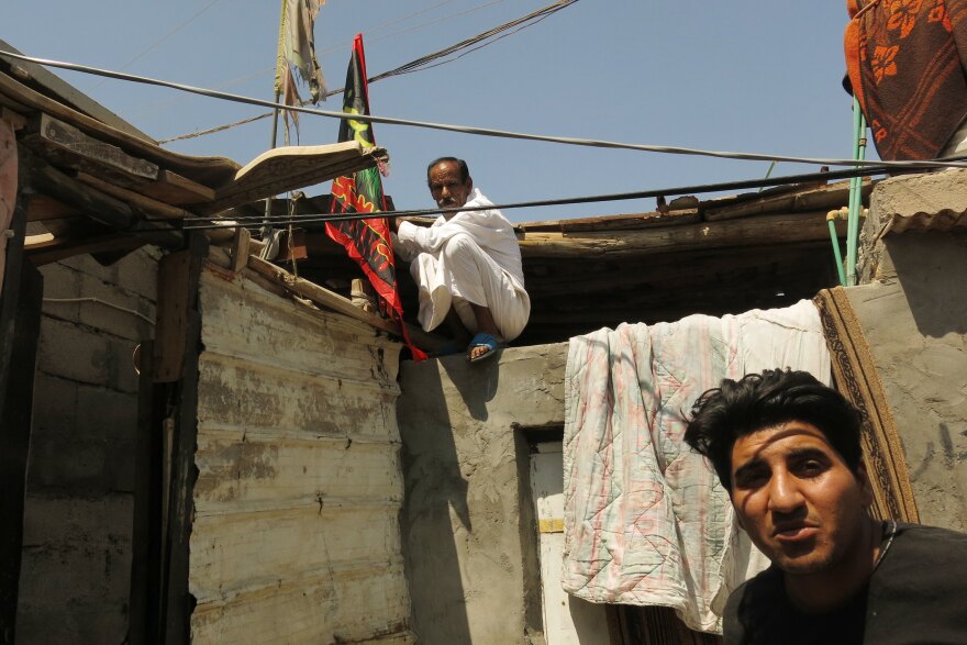 Ahmed Hussein (right) and his neighbor Kareen Khairala. Khairala is fixing a flag of Imam Hussein to the roof of his house in the al-Aleea neighborhood in Basra during the month of Muharram, when Shiite Muslims commemorate the battle of Karbala 14 centuries ago.