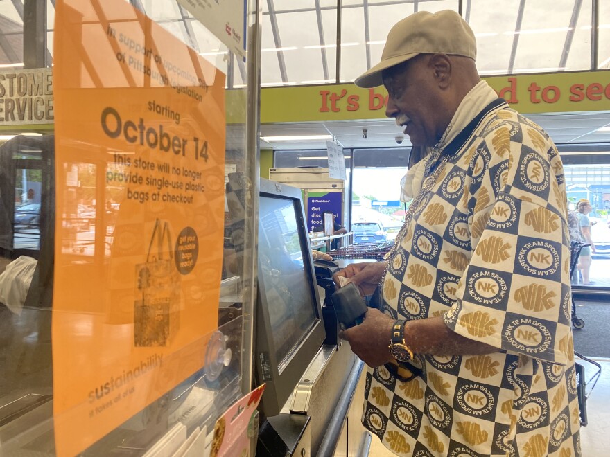 A customer at Giant Eagle checks out next to a sign with information about the city of Pittsburgh's plastic bag ban.