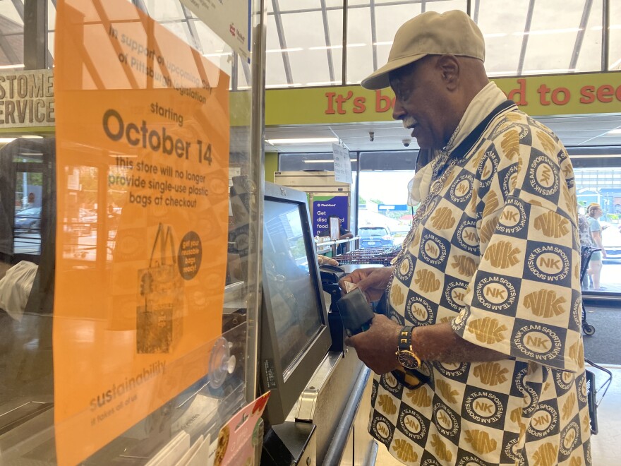 A customer at Giant Eagle checks out next to a sign with information about the city of Pittsburgh's plastic bag ban.