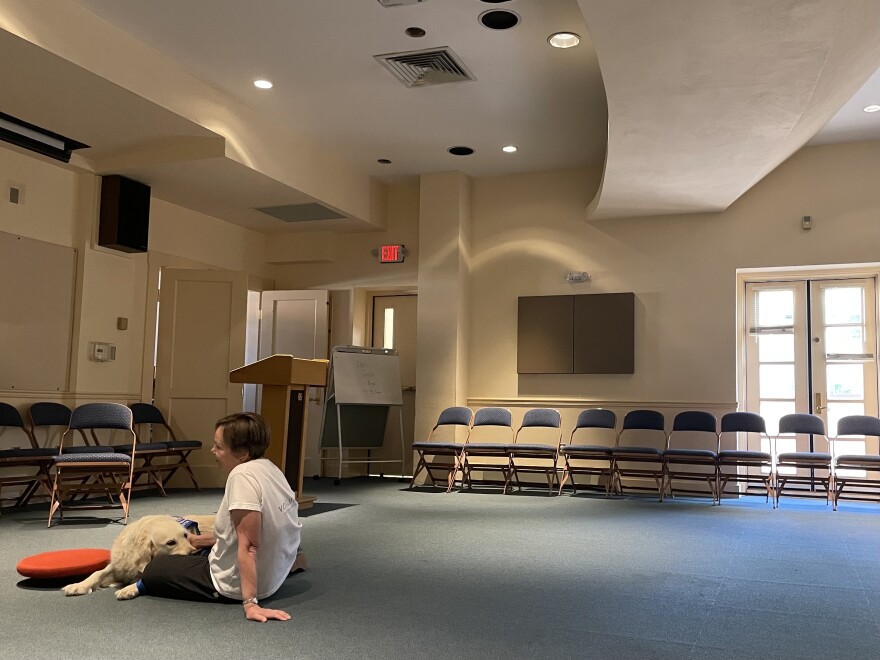 Sita and her owner Kathy Marsak sit on the floor and listen to a young reader at the Santa Fe Public Library's Wags and Words event in May 2023.