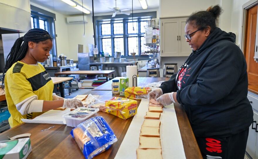 Zamiyah Keys, 13, and Courtney Holcombe prepare sandwiches for True Love Movement volunteers handing out valentines. They prepared a surf-and-turf dinner for single parents Wednesday evening.