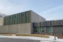 A photo of Davidson Elementary, a concrete school building with rainbow vertical lines on the facade and DAVIDSON spelled out in large letters cut out from the rainbow lines. 