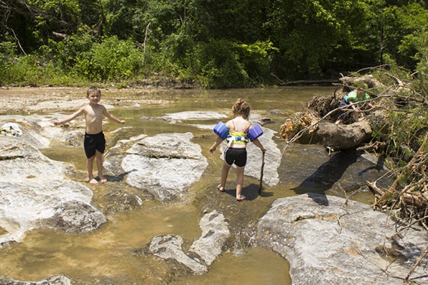 Children play in a small tributary of the Illinois River near Tahlequah, Okla., in May 2015.