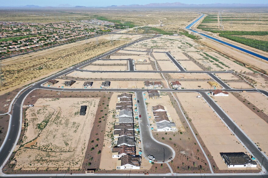 New homes are under construction in June at a housing development near Buckeye, Arizona. A growing number of local governments are considering limits on homebuilding in the face of floods, droughts and wildfires driven by climate change.
