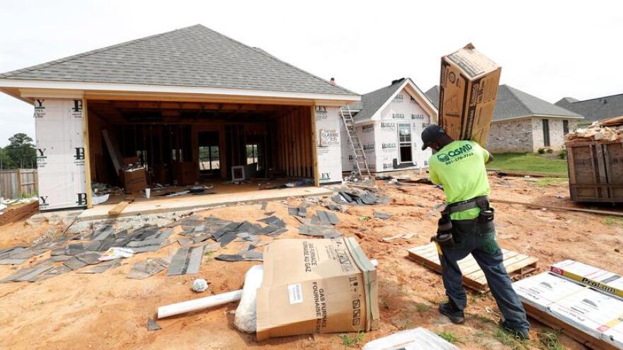 A worker carries supplies for a new house in this 2019 file photo.