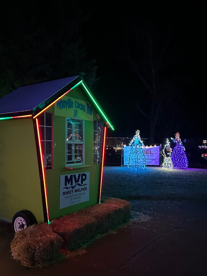 Small green hut with lights in background, sign reading “Whoville Cocoa Hut” 