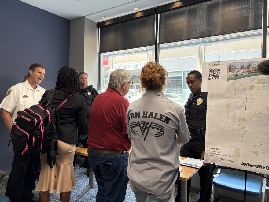 People talking at a public meeting on the Pedestrian Plaza.