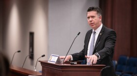 Man in suit speaks into podium