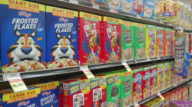 A grocery store shelf is filled with different Kellogg brand cereal boxes, each with their own colorful cartoon mascot.