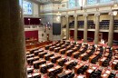 A view from the gallery of the floor of the Missouri House of Representatives. Rows of lawmakers desks and chairs are vacant. The carpet is a bold red and green. 