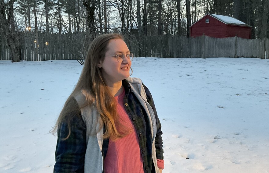 A woman stands in the snow looking into the distance