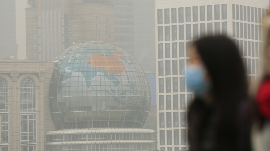 A woman wears a face mask on a hazy January day in downtown Shanghai. China has ordered a popular anti-pollution film removed from major online outlets. In Xi'an, two people who had protested against smog were reportedly detained.