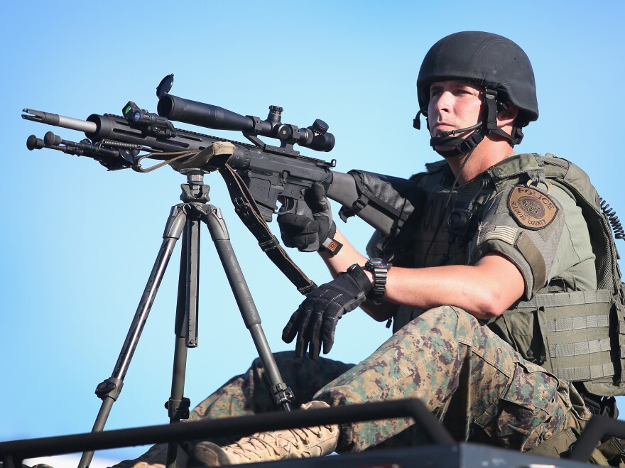 A police officer watches over demonstrators protesting the shooting death of teenager Michael Brown on Wednesday in Ferguson, Missouri. Brown was shot and killed by a Ferguson police officer on Saturday. Ferguson, a suburb north of St. Louis, has experienced three days of violent protests since the killing.