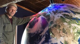 Artist Eric James Morris points out Fairbanks on a giant spherical model of Earth at the soon-to-be opened Aurora Discovery Institute at Pike’s Waterfront Lodge in Fairbanks. (Robyne/KUAC)