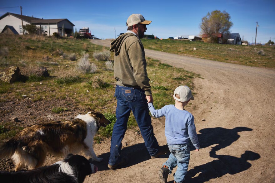 Chris Casad and his oldest son, Hesston, with dogs Beth, left, and her pup, Rue, walk along the driveway of the family’s farm.