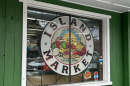 The window of a green building has a circular decal that says "Island Market"