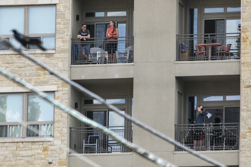 Austin residents watch a Thunderbirds flyover Wednesday afternoon from their apartment balconies.