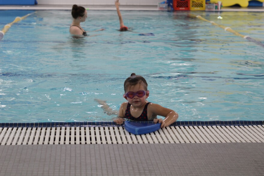Young girl in goggles floating at the side of the pool