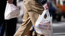 Pedestrians carry plastic bags in Philadelphia, Wednesday, March 3, 2021. Philadelphia and three other municipalities in Pennsylvania sued the state Wednesday over what they say was a covert abuse of legislative power to temporarily halt local bans or taxes on plastic bags handed out to customers by retailers.