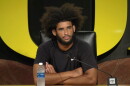 A man sits at a table in front of a microphone