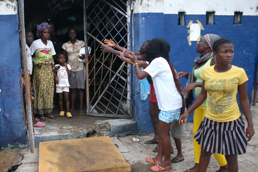 Residents beckon patients to leave the Ebola holding center.