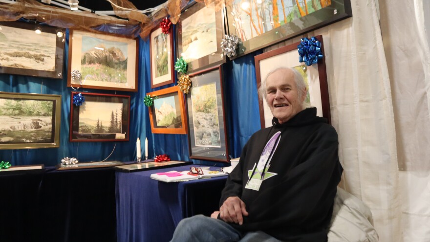 A man sits in a booth in front of paintings