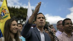 Venezuela's self-declared interim leader Juan Guaido, accompanied by his wife Fabiana Rosales, speaks to supporters during a gathering to propose amnesty laws for police and military, at a public plaza in Las Mercedes neighborhood of Caracas, Venezuela, Saturday, Jan. 26, 2019. Venezuela's political showdown moves to the United Nations where a Security Council meeting called by the United States will pit backers of President Nicolas Maduro against the Trump administration and supporters of Guaido. (AP Photo/Rodrigo Abd)