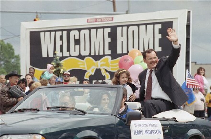 Terry Anderson waves from a car in a parade