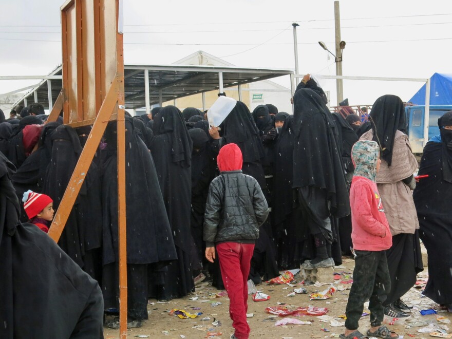 Women and children wait for distribution of food at the al-Hol camp in northeastern Syria. Most are family members of ISIS fighters, viewed by the region's Kurdish Syrian leadership as a potential danger. Iraq says it wants to bring back 30,000 of its citizens to place in Iraqi camps, but few are willing to return.
