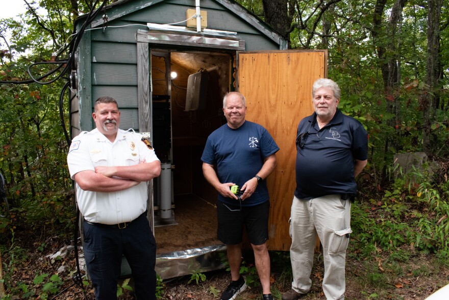 Fire Chief John Coffey (left) and volunteer firefighters David Billstrom and Borden Borden stand atop Allen Mountain, where the VHS repeater boosts the backup radio network for Black Mountain.