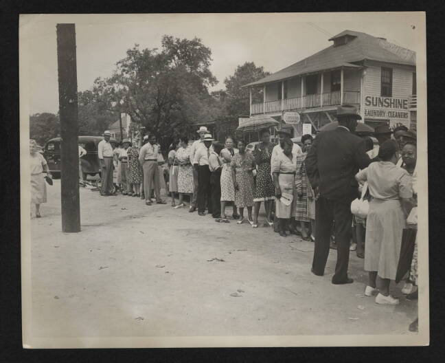 Black voters in front of the Sunshine Laundry and Cleaners wait to cast ballots for the first time in a statewide Democratic primary, Aug. 10, 1948.