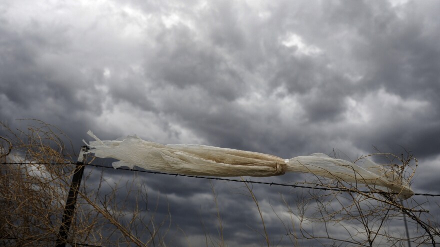 A plastic bag caught on a fence blows in the wind. Microplastic is formed from larger pieces of plastic that have broken down.