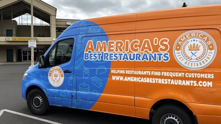 Promotional truck parked outside bagel shop. 