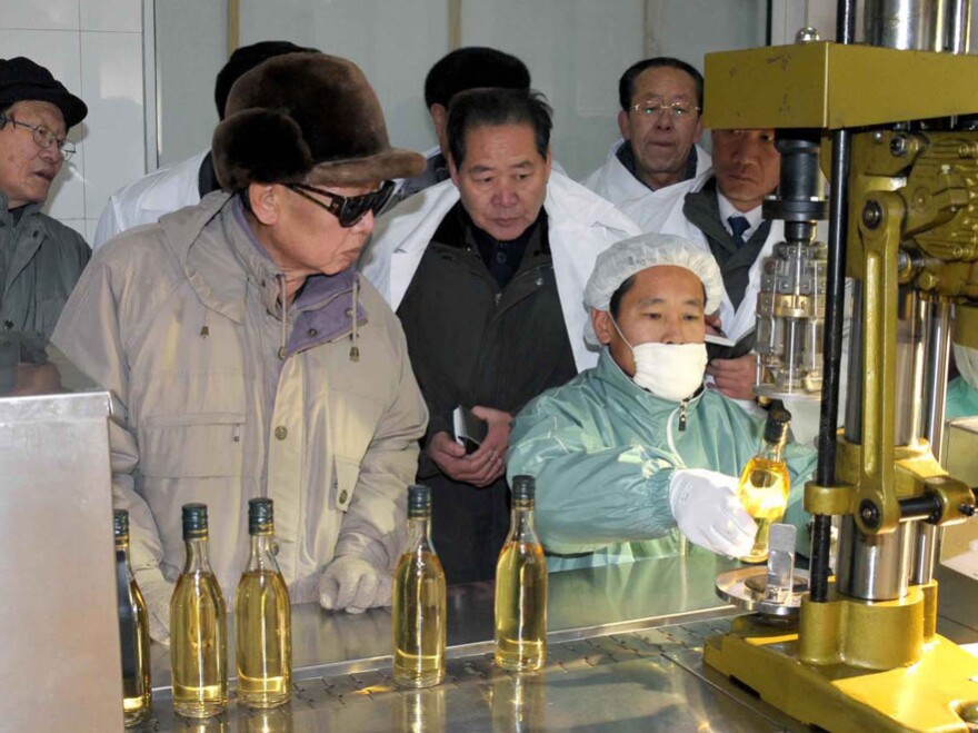 In this undated photo released by Korean Central News Agency via Korea News Service in Tokyo December 2009, North Korean leader Kim Jong Il, left, looks at a bottle containing an alcoholic beverage as he visits a factory of the Rason Taehung Trading Company in North Hamgyong Province, North Korea.