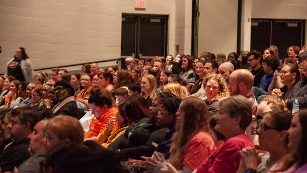 A large crowd faces forward in a packed auditorium.