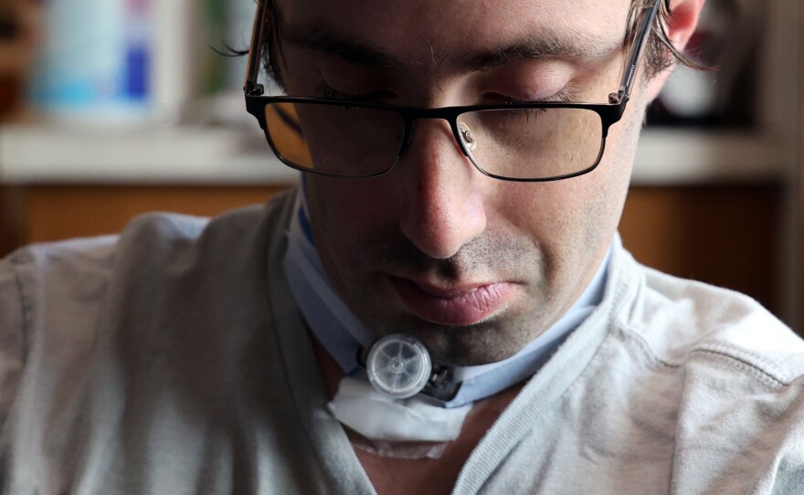 Kyle Smith stares at his tracheotomy tube after cleaning it out at his home on Gainesville, Fla., Friday, Feb. 7, 2025. (Ashleigh Lucas/WUFT News)