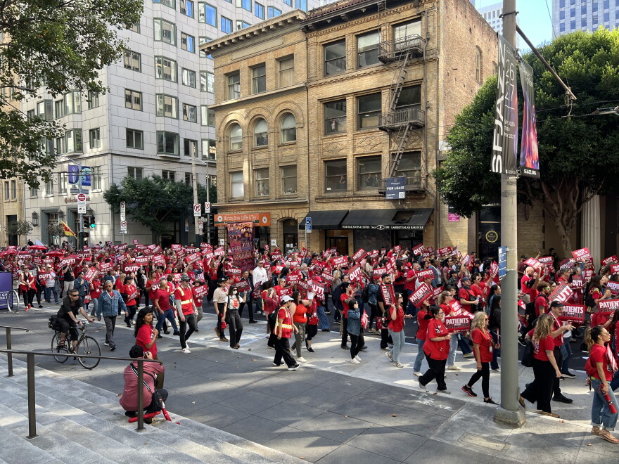 A crowd of nurses wearing red march down the street.