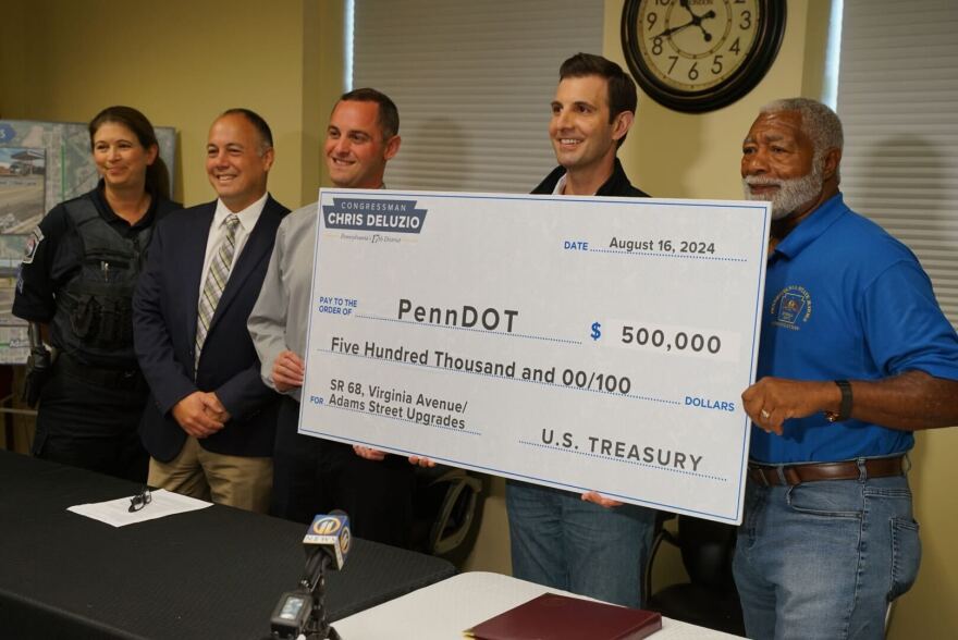 Rep. Chris Deluzio poses with the mayor of the borough of Rochester, in Beaver County, along with state highway officials, during an event announcing federal funding that will go to help redo one of the borough's main roads.