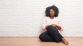 Young african american woman sitting on the floor at home depressed and worry for distress, crying angry and afraid. Sad expression.