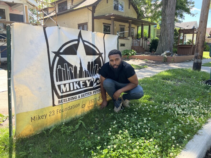 Rico Stewart poses outside of the South Rundle Street house in front of the Mikey 23 Foundation sign on June 16, 2022.