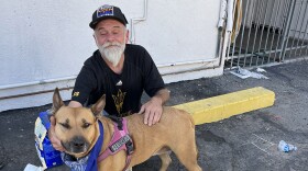 Man pets his dog while sitting in parking lot