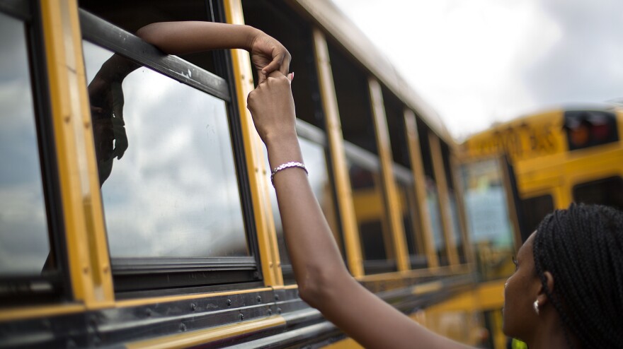 Laterrica Luther holds the hand of her 6-year-old nephew, Jaden Culpepper, as students from the Ronald E. McNair Discovery Learning Academy arrive on buses to waiting loved ones in a Walmart parking lot in Decatur, Ga., on Tuesday. A gunman had entered the students' school earlier in the day. No one was hurt.