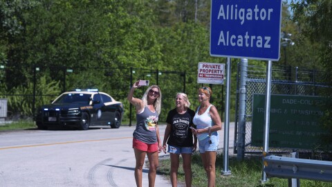 A group of women pose for a selfie in front of the "Alligator Alcatraz" sign at the entrance to an immigration detention center in the Florida Everglades, Thursday, Aug. 28, 2025, in Collier County.