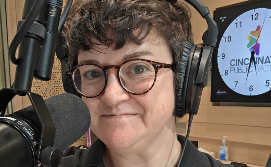 A person wearing headphones standing behind a microphone