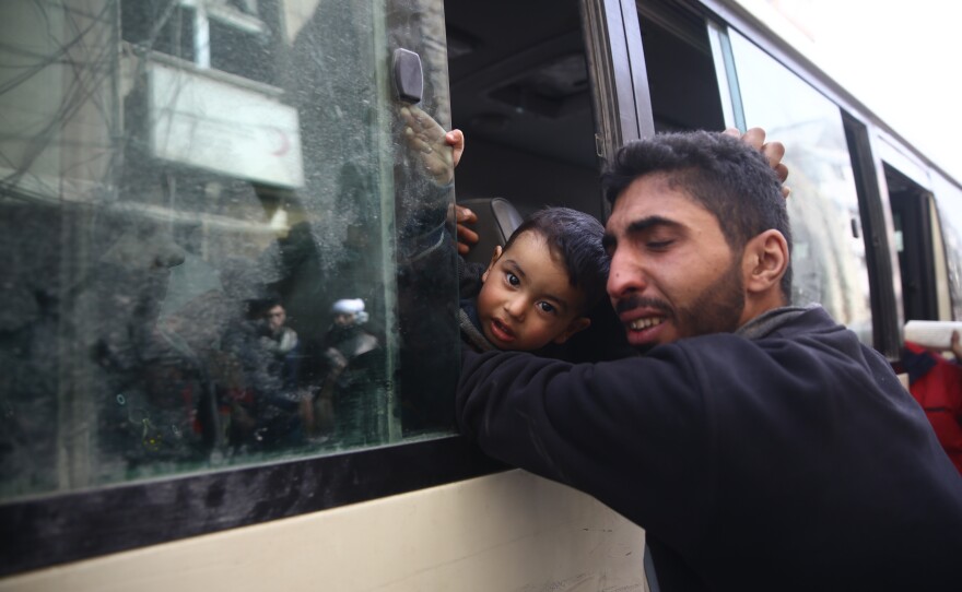 <strong>March 19, 2018:</strong> <em>Douma</em> — A man hugs his child before the boy is evacuated during a break in the bombing campaign. The fighting between the government and the rebels holding Eastern Ghouta forced many men to separate from their children and families.
