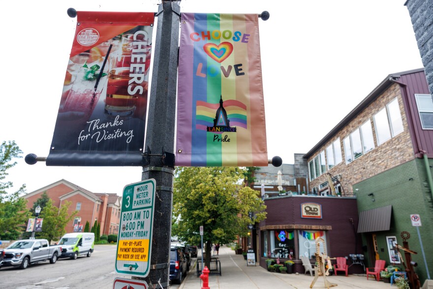 Two street pole banners in Old Town Lansing, one says "Choose Love" with rainbows, another says "Cheers, Thanks for visiting"