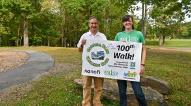 Valley in Motion President Gus Fahey and Roxy Brown, recreation access specialist, hold a sign for Connell Park Walking Club's 100th walk.
